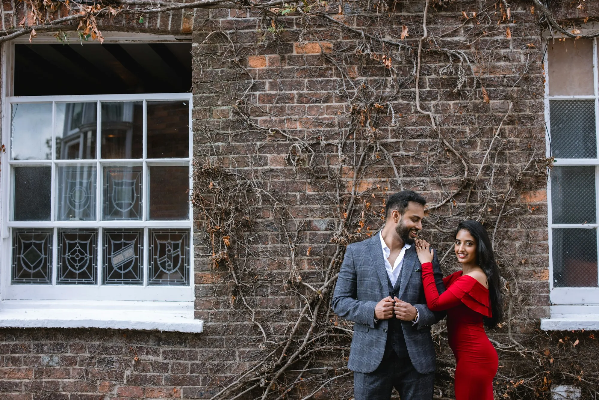 Couple standing together in front of a brick house